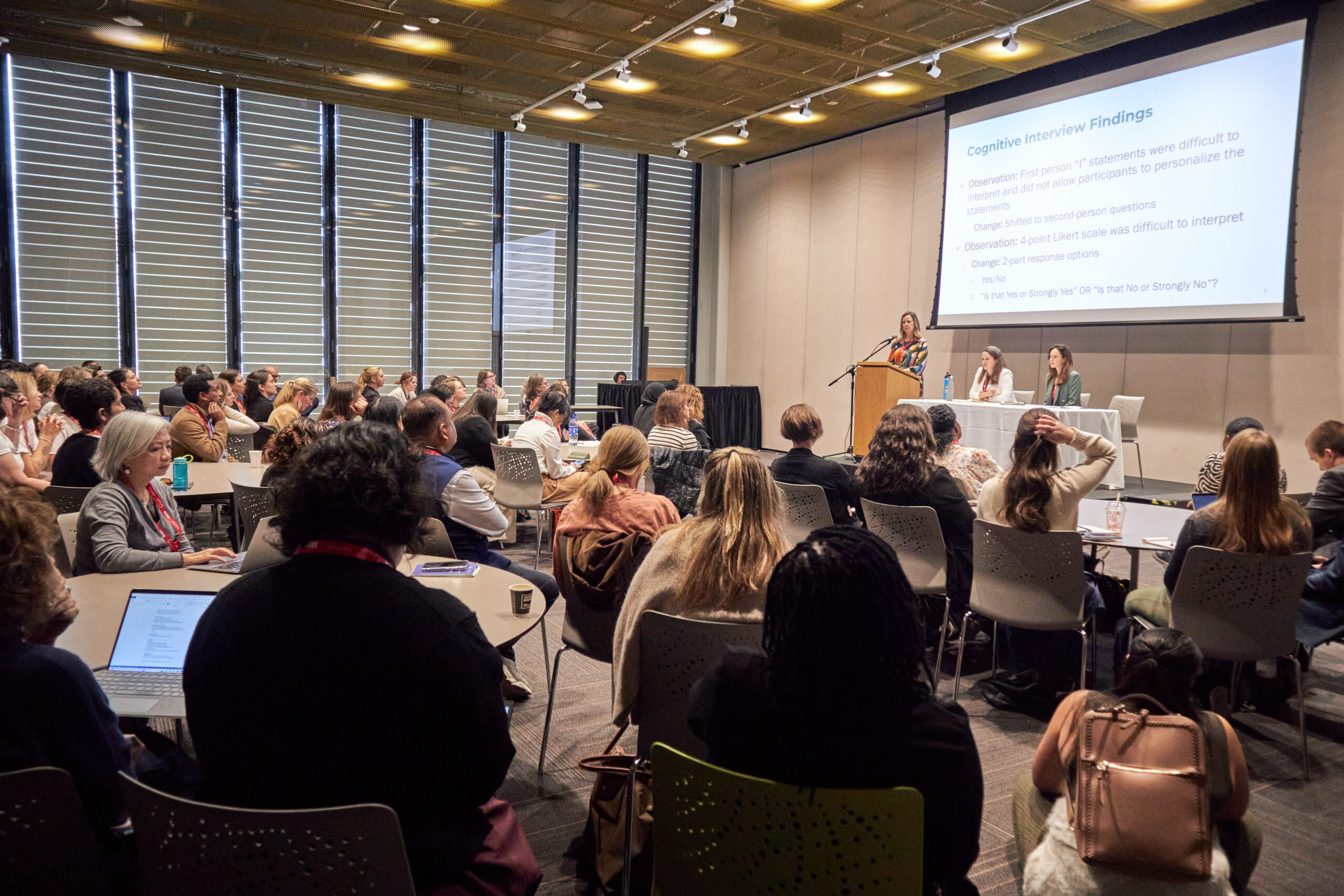 a full room of people listening to a scientific presentation