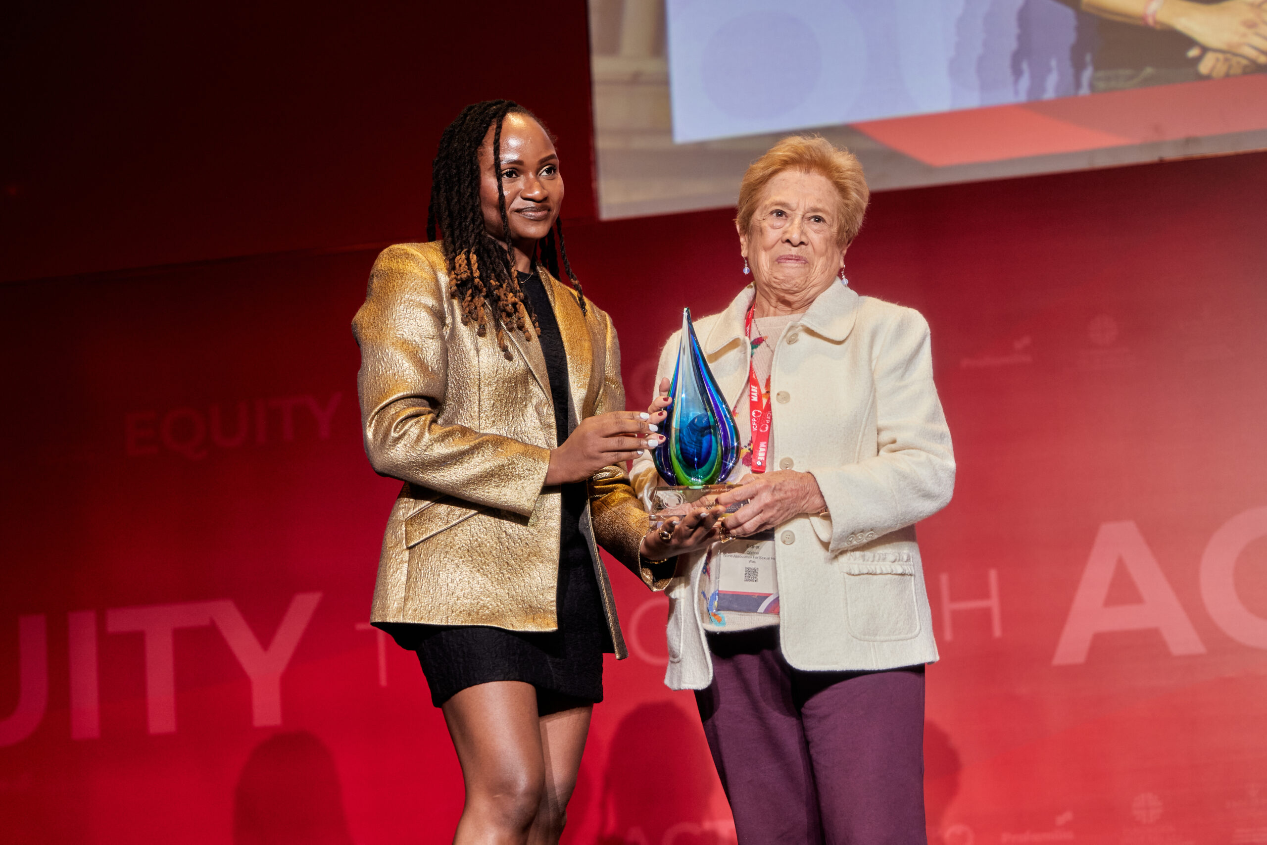 A woman accepting an award from another woman on a stage