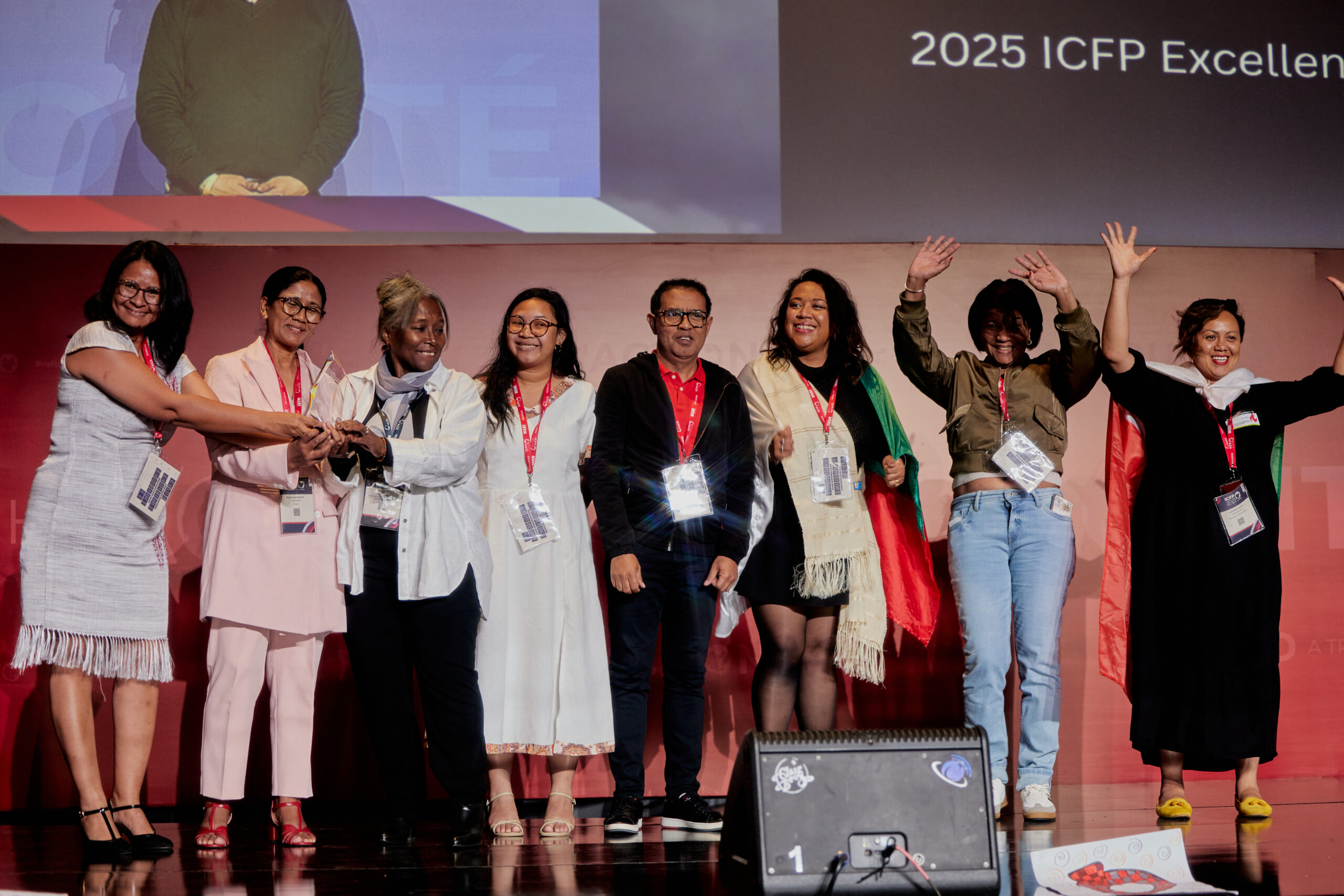 A group of individuals on stage with their arms out and holding their award