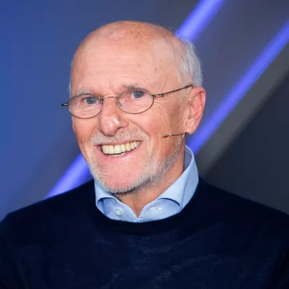 Headshot of a man in a collared shirt speaking with a headset