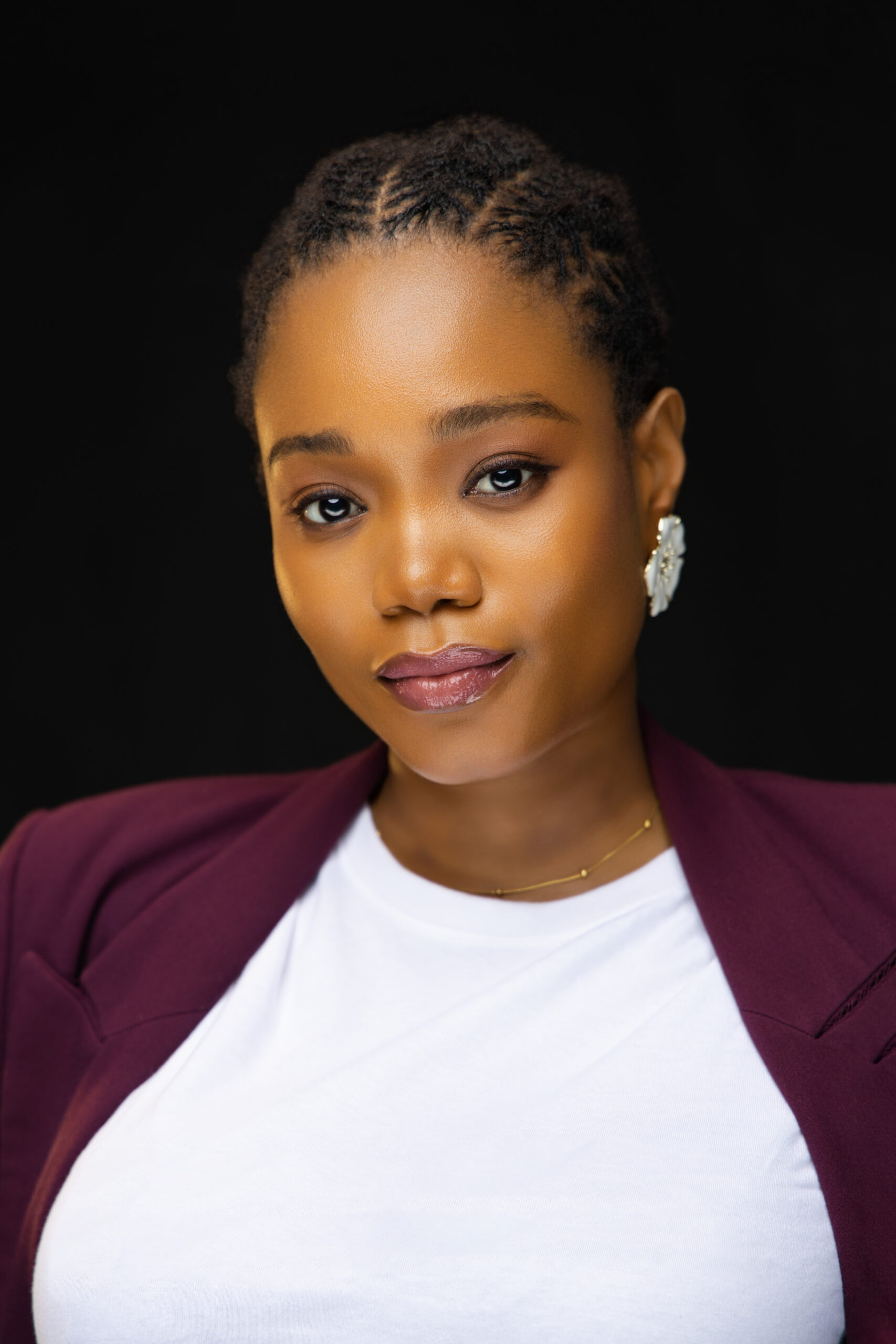 Headshot of a woman in a maroon blazer with a black background