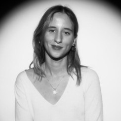 Headshot of a woman in a maroon blazer with a black background