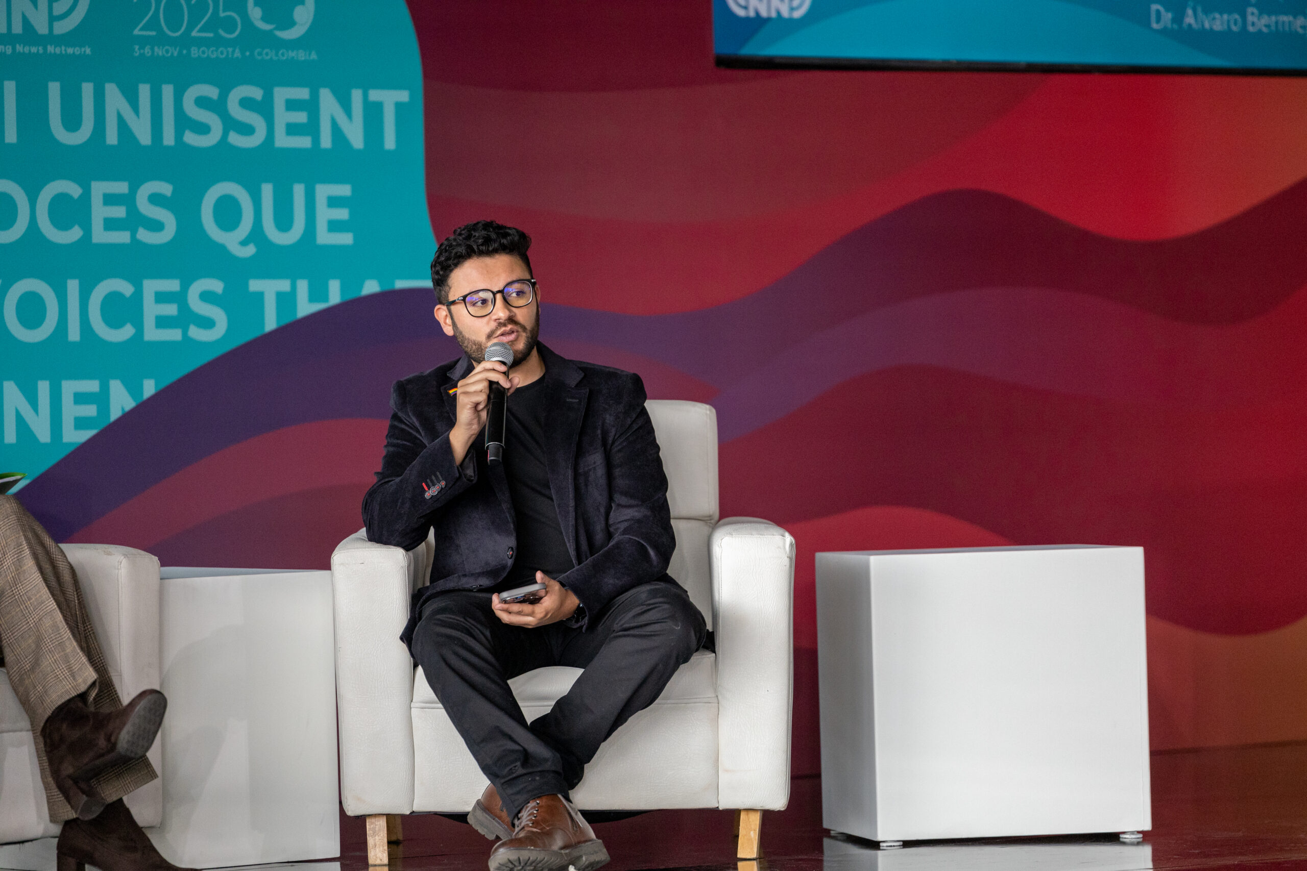 Christian A man sitting in a white chair on a stage