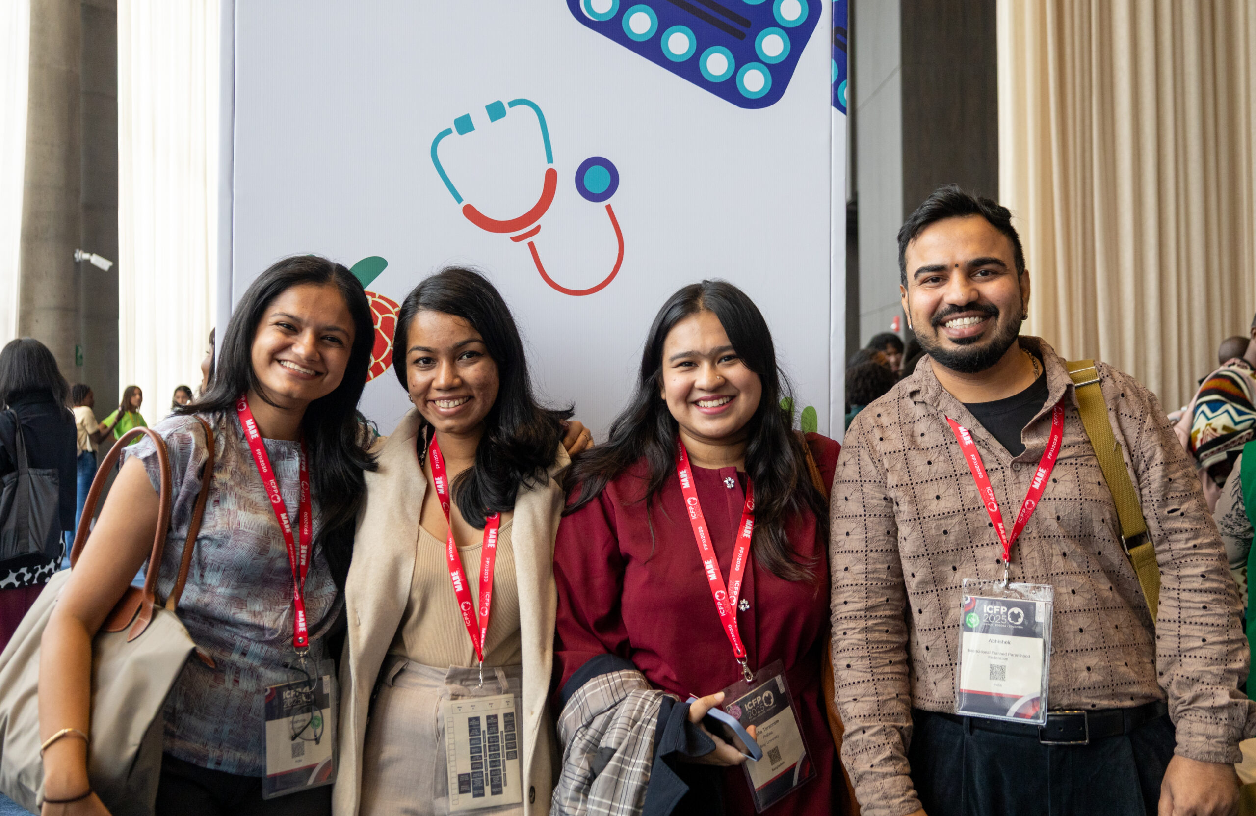 Four young people smiling and wearing conference badges